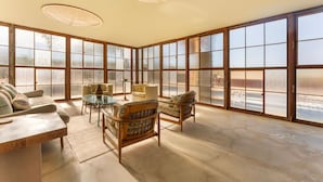 Una habitación amplia con ventanas grandes, una mesa de madera y asientos cómodos.
