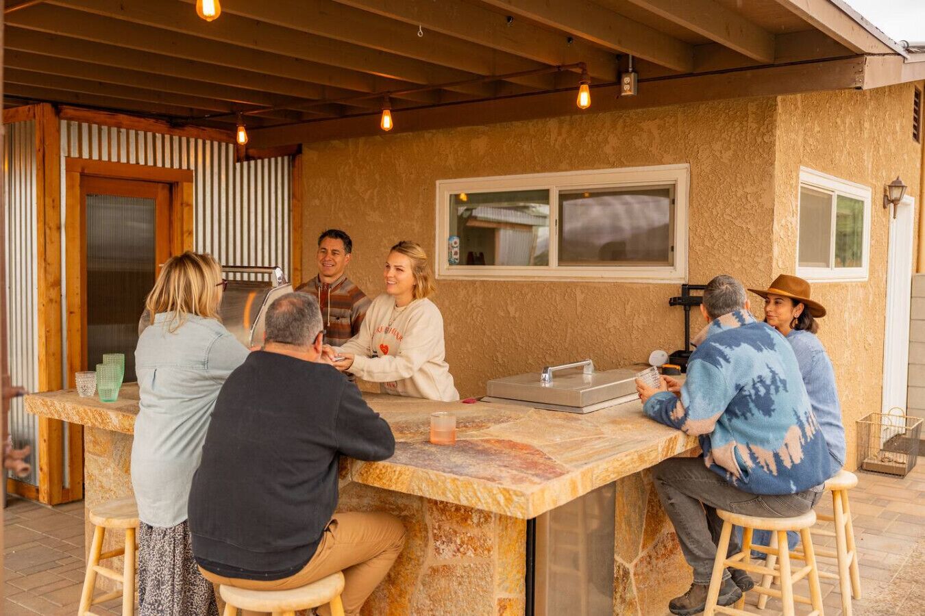 A group of people seated around a stone bar with a window above it.