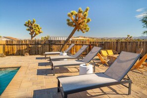 A poolside area with lounge chairs, a small pool, and a wooden fence. - Flutter Space Retreat | Yoga Dome | Pool (Yucca Valley)