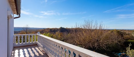 A balcony with a view of a hilly landscape.