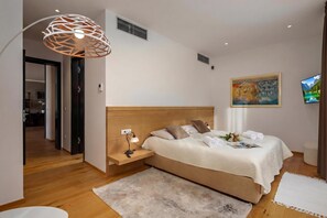 A modern bedroom with a wooden bed, bedside table, lamp, and a painting on the wall. - Luxury Pool & Spa Villa Miracle (Brtonigla)