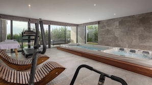 A modern spa area with a massage table, wooden benches, a treadmill, and a hot tub. - Luxury Pool & Spa Villa Miracle (Brtonigla)