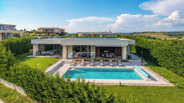 A modern house with a swimming pool, surrounded by lush greenery and a clear blue sky. - Luxury Pool & Spa Villa Miracle (Brtonigla)