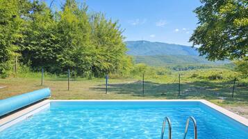 Una piscina con agua cristalina azul, rodeada de exuberante vegetación y una montaña al fondo.