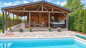 Un espacio exterior cubierto con piscina, terraza de madera y mobiliario.