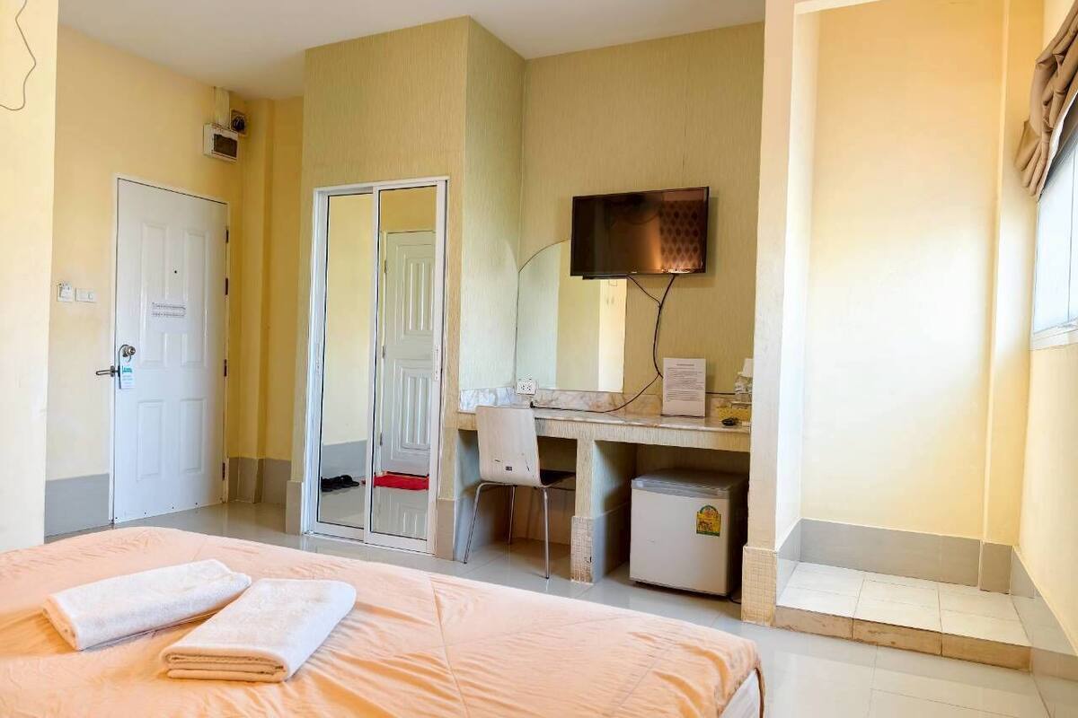 Une chambre d’hôtel équipée d’un lit, d’un bureau, d’une chaise, d’une télévision et d’un petit réfrigérateur.