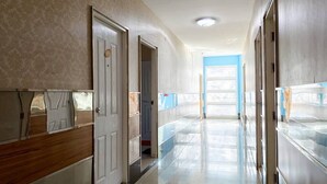 A hallway with doors leading to rooms, a tiled floor, and a blue wall at the end. - Veerakit Grand Hotel Udon Thani (Udon Thani)