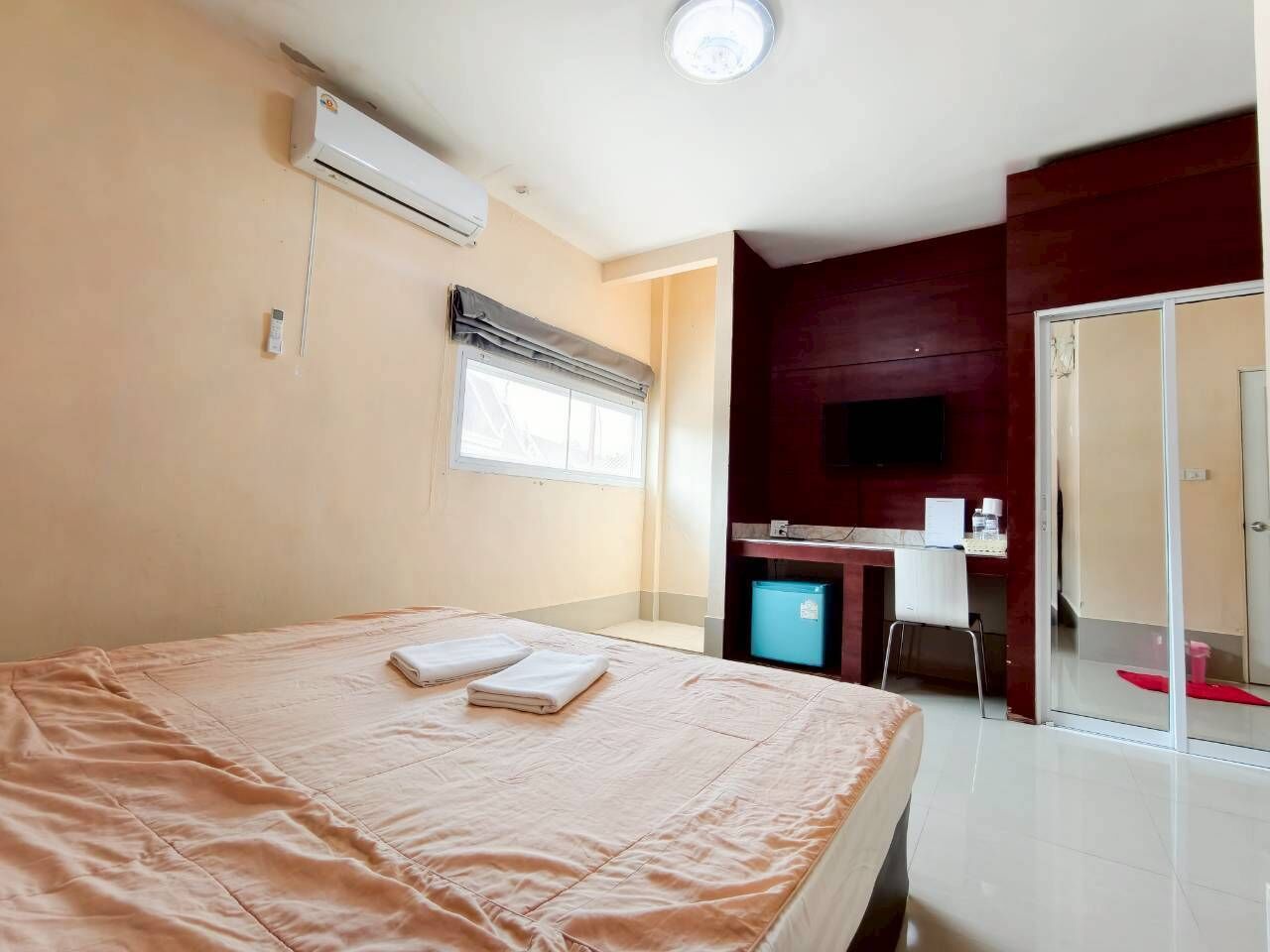 A hotel room with a bed, a desk, a television, and a sliding door.