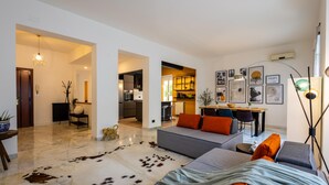 Un soggiorno moderno con un divano, un'area pranzo e una cucina visibile attraverso un arco aperto.