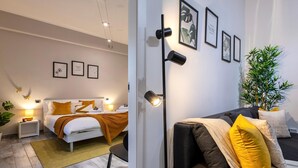 Una habitación de hotel moderna con una cama, una mesita de noche, una lámpara y un sofá con cojines.