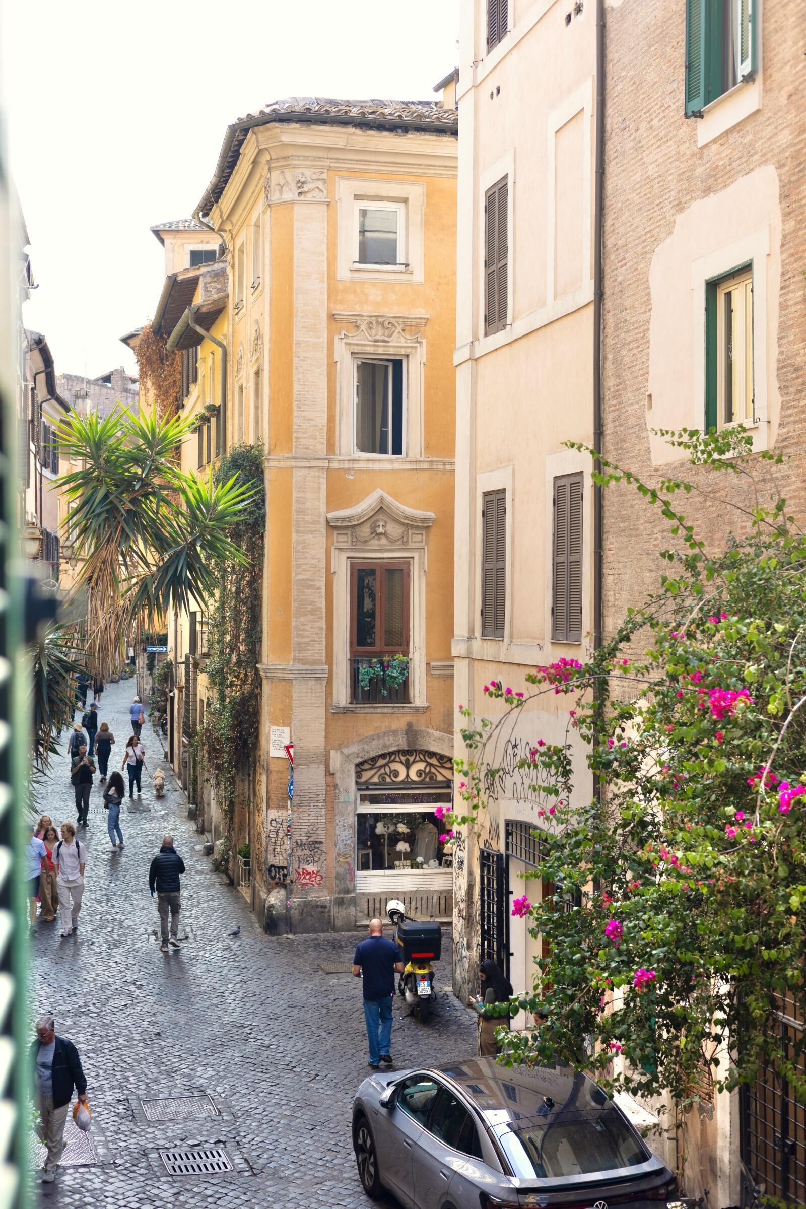 A cobblestone street lined with historic buildings, narrow passageways, and pedestrians.