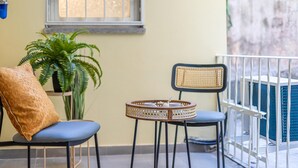 Een balkon met twee stoelen, een kleine tafel en een potplant.