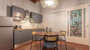 Een moderne keuken met grijze kastjes, een ingebouwde oven en een eethoek met een ronde tafel en stoelen.