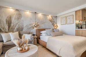 A modern bedroom with a large bed, a sofa, a round coffee table, and a wall with abstract art. - Waikiki Luxe Haven – Chic Comfort in Paradise (Honolulu)
