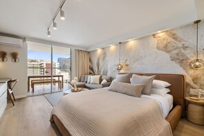 A modern bedroom with a large bed, a sofa, and a dining area. - Waikiki Luxe Haven – Chic Comfort in Paradise (Honolulu)