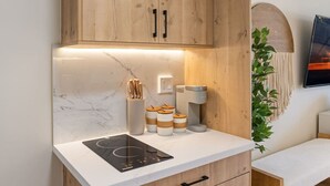 Una cucina moderna con mobili in legno, schienale in marmo, piano cottura a induzione integrato e macchina da caffè.