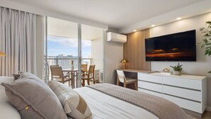 A modern hotel room with a large bed, a desk, and a TV. - Waikiki Ocean Luxe Retreat High Floor Suite (Honolulu)