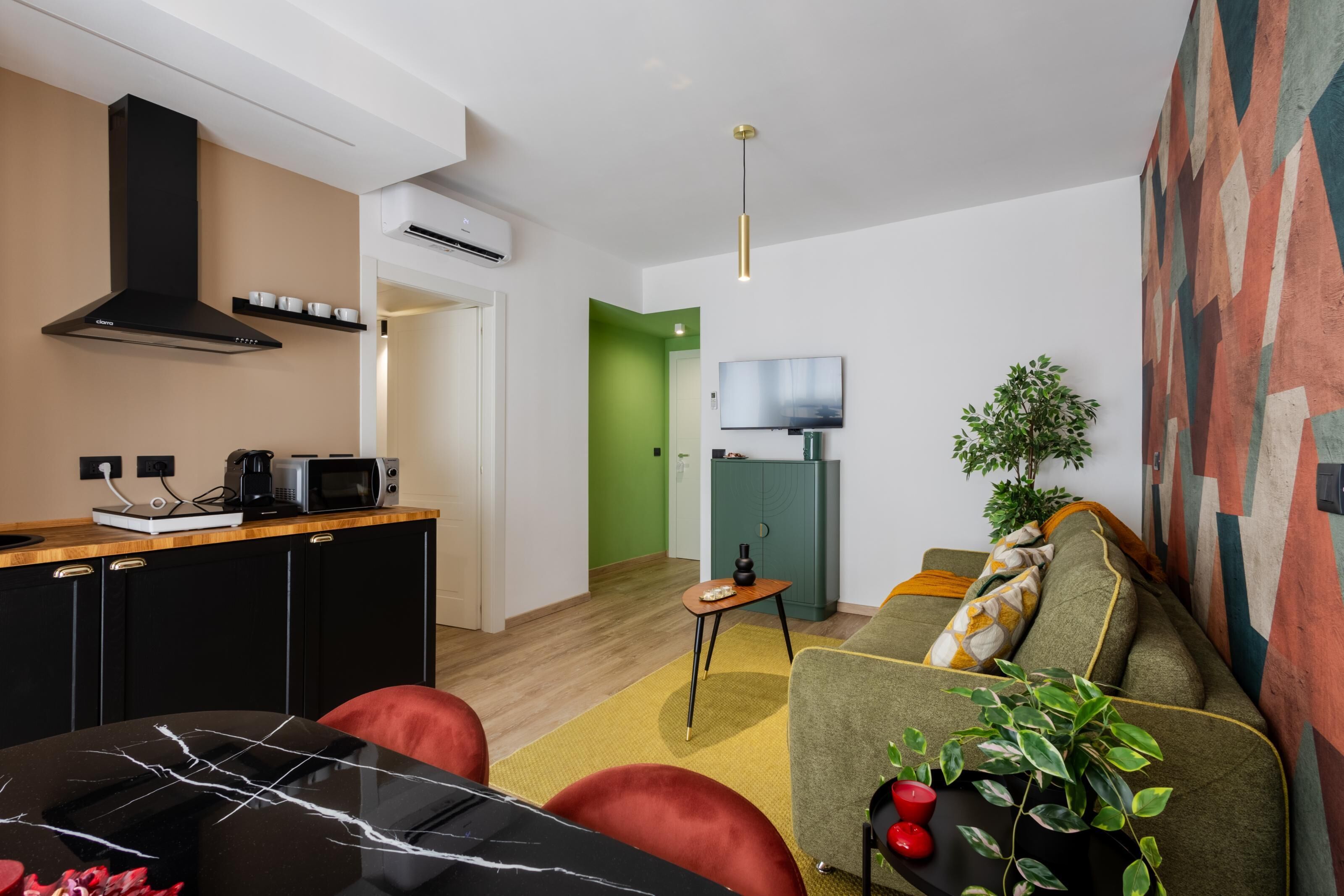A modern living space with a kitchen, dining area, and a TV mounted on the wall.