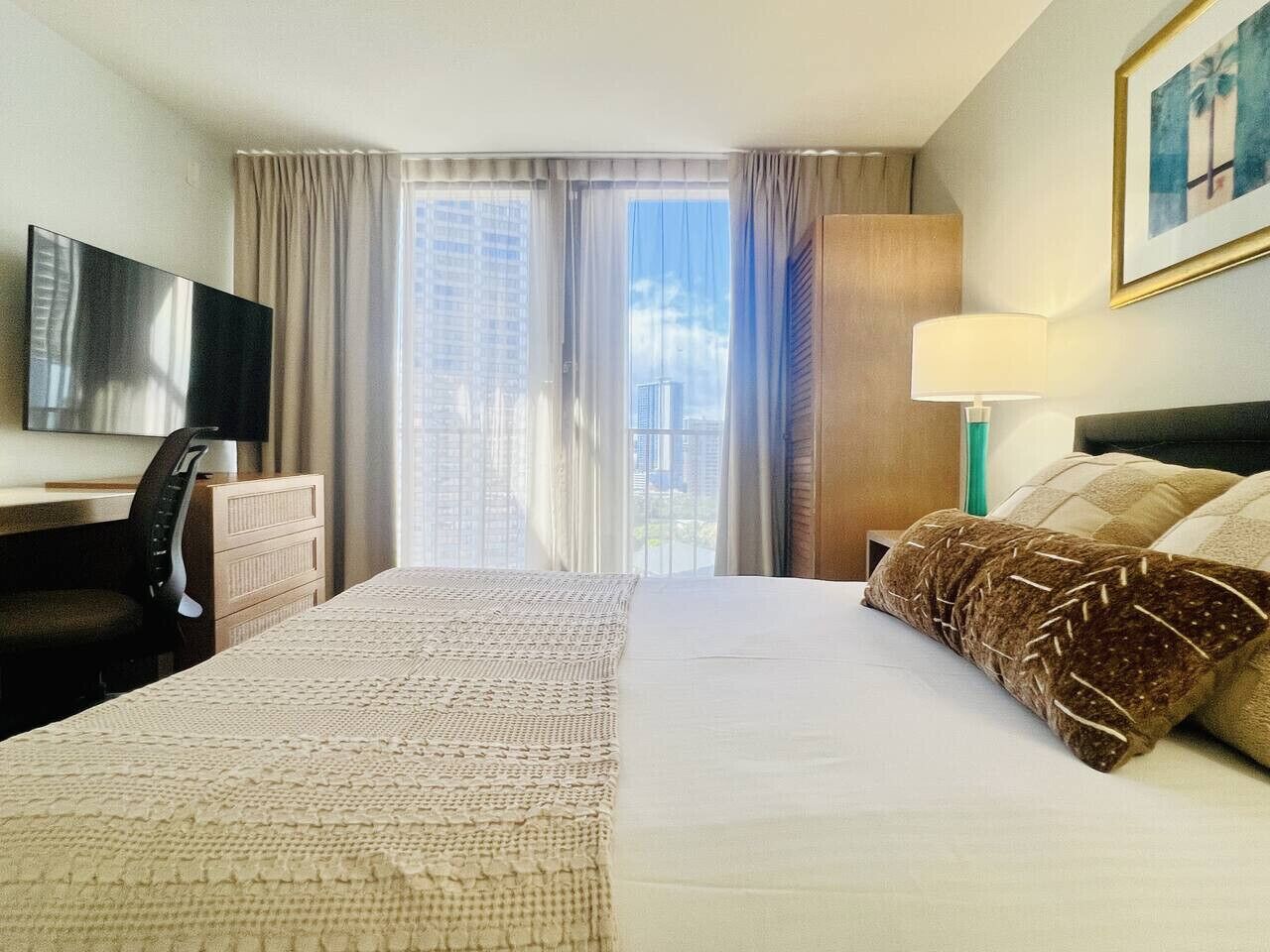Une chambre d’hôtel avec un grand lit, un bureau avec une chaise, une télévision et une fenêtre avec des rideaux.