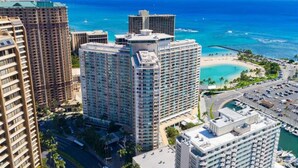A high-rise hotel with multiple floors, a marina with boats, and a beach in the background. - Waikiki Wave Retreat: Ocean Luxe on 17F (Honolulu)