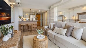 A modern living room with a sofa, a coffee table, and a kitchen area in the background. - Waikiki Wave Retreat: Ocean Luxe on 17F (Honolulu)