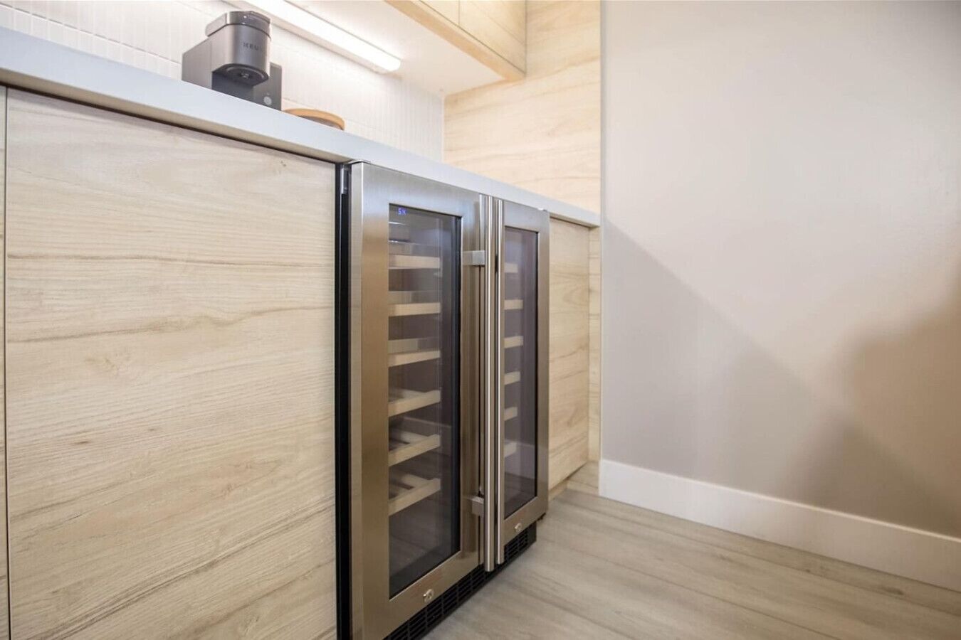 A modern kitchen with stainless steel appliances, wooden cabinetry, and a light-colored floor.