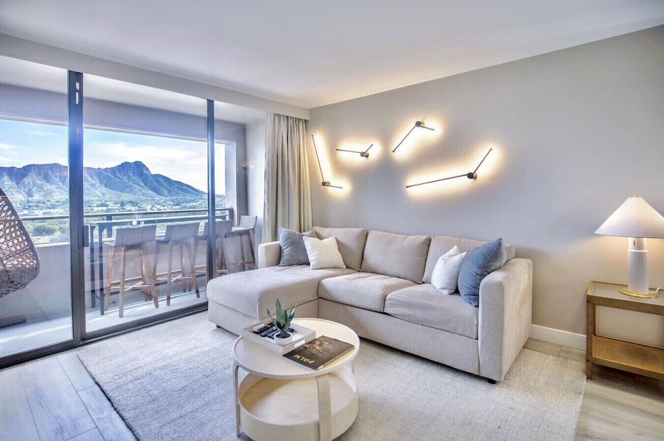 Una sala de estar moderna con un ventanal grande, un sofá, una mesa de centro y una lámpara.