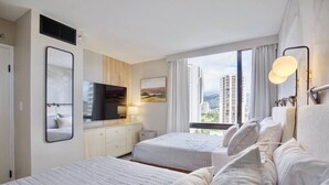 Ein Hotelzimmer mit zwei Betten, einem Fernseher, einem Fenster mit Blick auf die Stadt und einem großen Spiegel.