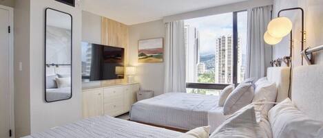 Habitación de hotel con dos camas, televisión, ventana con vista a la ciudad y un espejo grande.