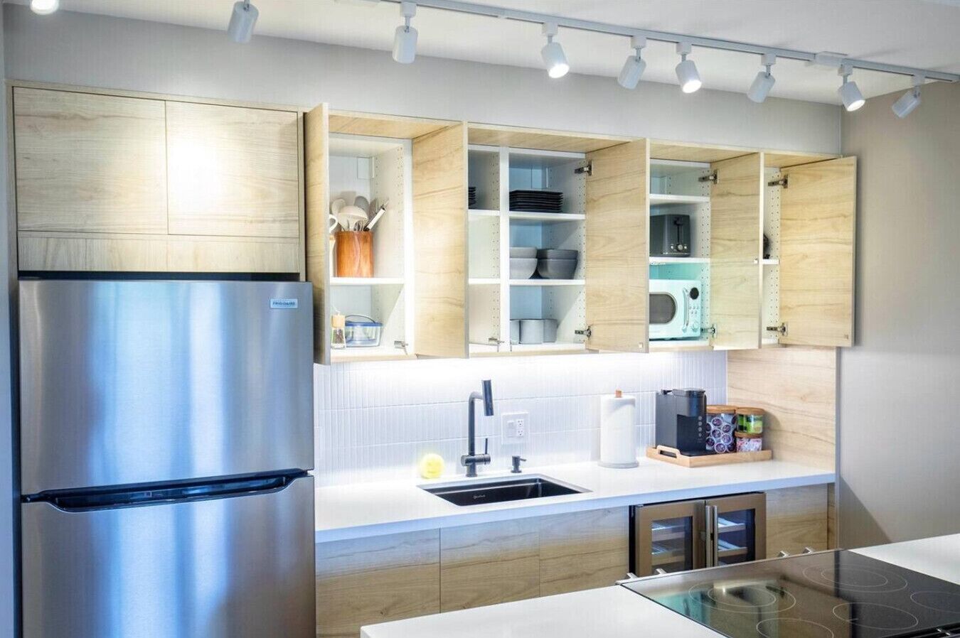 A modern kitchen with a stainless steel refrigerator, wooden cabinets, and a built-in microwave.