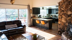 A modern living room with a leather sofa, a coffee table, and a fireplace. - Hot Tub, Walk to Town, Lake Access, Fireplace, Fenced Yard (Twain Harte)