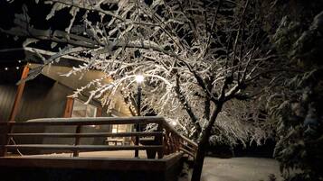 A snow-covered outdoor area with a wooden bench and a building in the background.