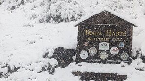 A snow-covered sign with 'Twain Harte Welcomes You' and various logos. - Hot Tub, Walk to Town, Lake Access, Fireplace, Fenced Yard (Twain Harte)