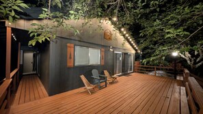 Une terrasse en bois avec deux chaises, une fenêtre et une porte.