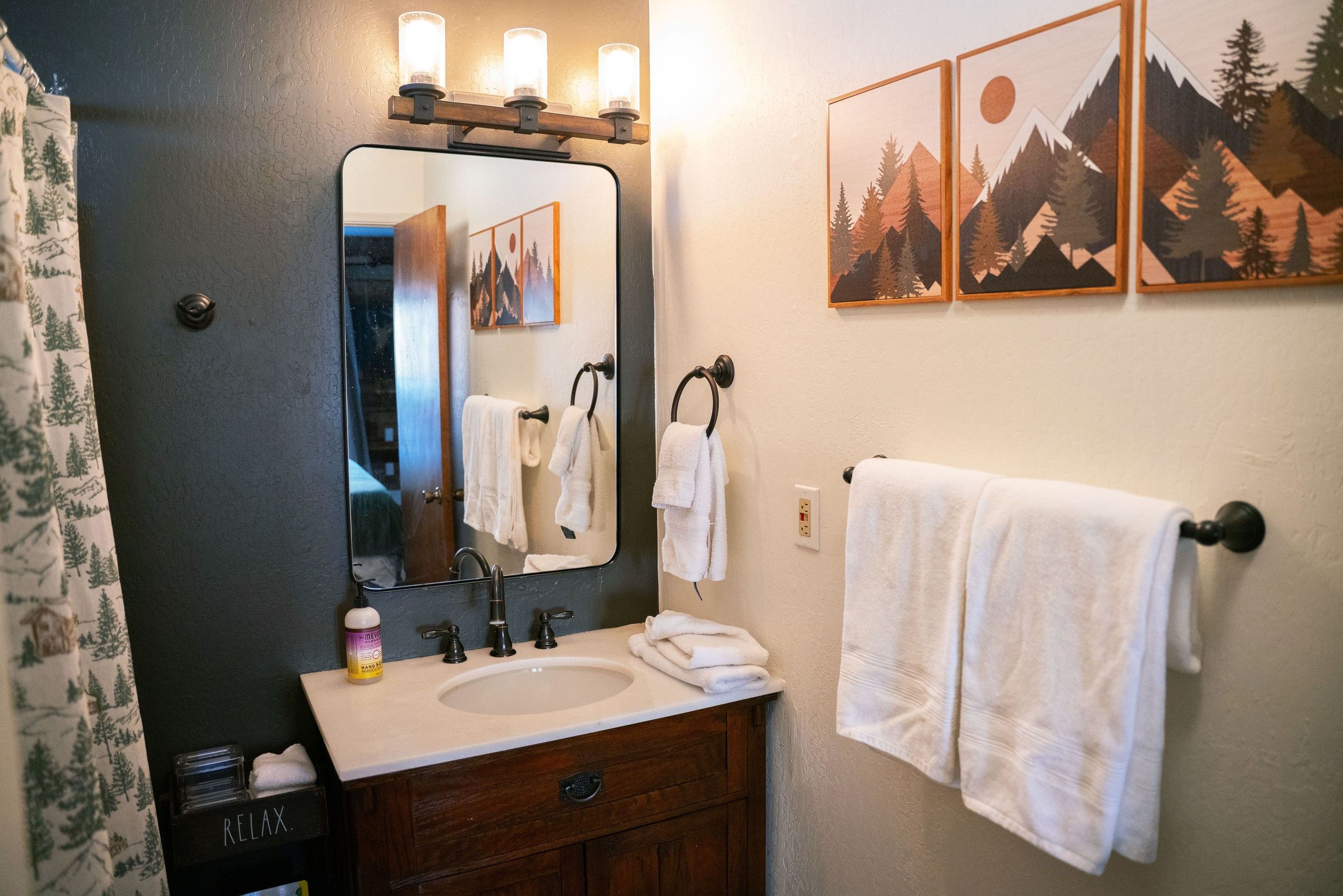 Une salle de bain avec un miroir, un lavabo et trois serviettes accrochées au mur.