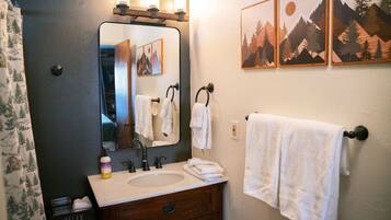 Une salle de bain avec un miroir, un lavabo et trois serviettes accrochées au mur.