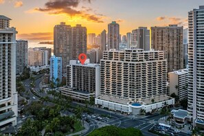 A high-rise urban area with multiple apartment buildings, a central road, and a body of water in the background. - Waikiki Ocean Breeze: A Peaceful Island Getaway (Honolulu)
