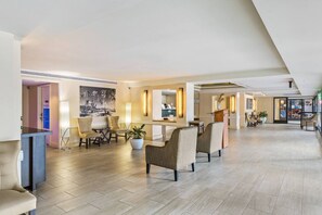 A spacious hotel lobby with a high ceiling, a reception desk, seating areas, and a large painting on the wall. - Waikiki Ocean Breeze: A Peaceful Island Getaway (Honolulu)