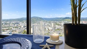 A table with a candle, a glass, and a starfish, with a cityscape and mountains in the background.