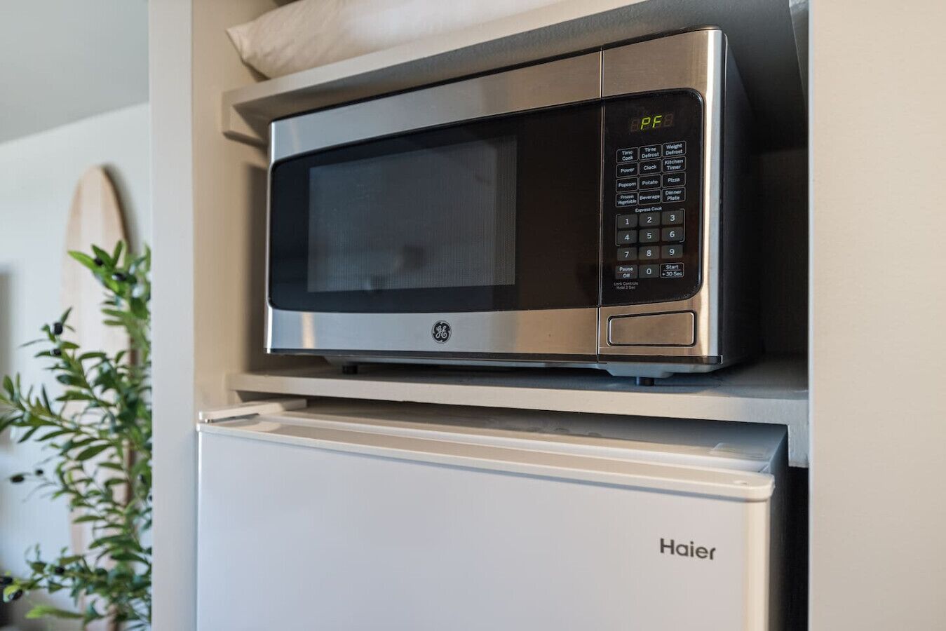 Eine kleine Küche mit einer Edelstahl-Mikrowelle auf einem weißen Kühlschrank.