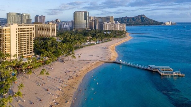 A coastal cityscape with a beach, high-rise buildings, and a pier extending into the ocean. - Corner Bliss in the Heart of Waikiki 8F (Honolulu)