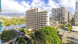 A high-rise hotel with multiple balconies, a swimming pool, and a view of a river and surrounding greenery. - Corner Bliss in the Heart of Waikiki 8F (Honolulu)