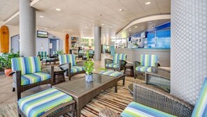 A spacious lobby with wicker furniture and striped cushions, a reception area with a counter, and a large pillar. - Corner Bliss in the Heart of Waikiki 8F (Honolulu)