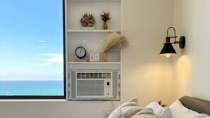 Ein Schlafzimmer mit einem Bett, Kissen, einem an der Wand befestigten Regal mit Dekoration, einer Uhr und einer Klimaanlage.