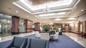 A hotel lobby with a central seating area, a reception desk, and a staircase leading to an upper level. - Urban Oasis in Honolulu: Comfort & Parking (Honolulu)