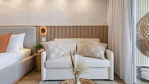 Ein modernes Wohnzimmer mit einer Sofagarnitur, einem Beistelltisch mit Pflanze und einer dekorativen Vase mit Trockenblumen.