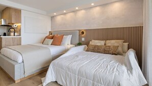 Ein modernes Schlafzimmer mit zwei Betten, einem Einbauschrank und einer kleinen Küchenzeile.
