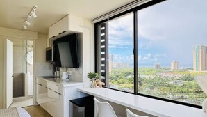 Een moderne keuken met een groot raam, een flatscreen-tv en uitzicht op een stadsgezicht.