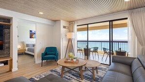 A modern living room with a sofa, a teal armchair, and a round wooden coffee table. There is a balcony with a view of the sea. - Waikiki Ocean Luxe Panorama 2BD, Free Parking (Honolulu)
