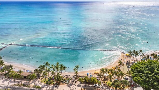 A beach with clear turquoise waters, palm trees, and a sandy shore. - Waikiki Ocean Luxe Panorama 2BD, Free Parking (Honolulu)